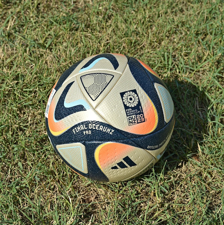Pallone Adidas Oceaunz Final Pro – vista completa su erba con grafica oro e motivi Maori