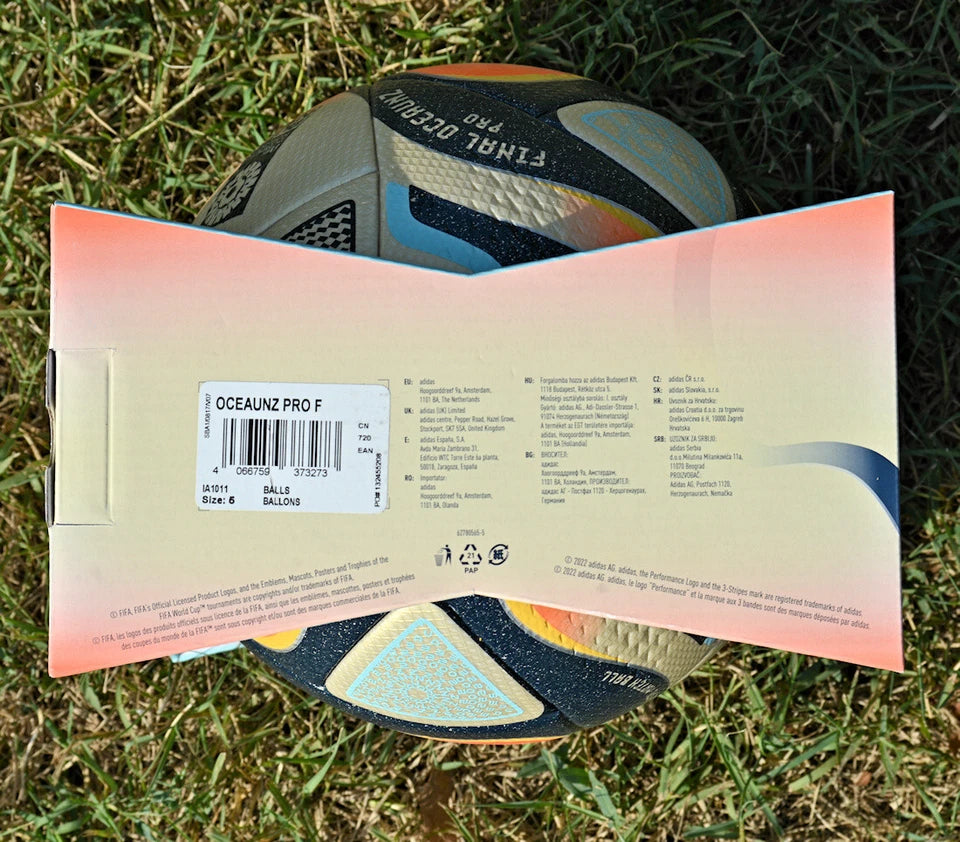 Pallone Adidas Oceaunz Final Pro – vista laterale su erba con pannelli oro e blu scuro
