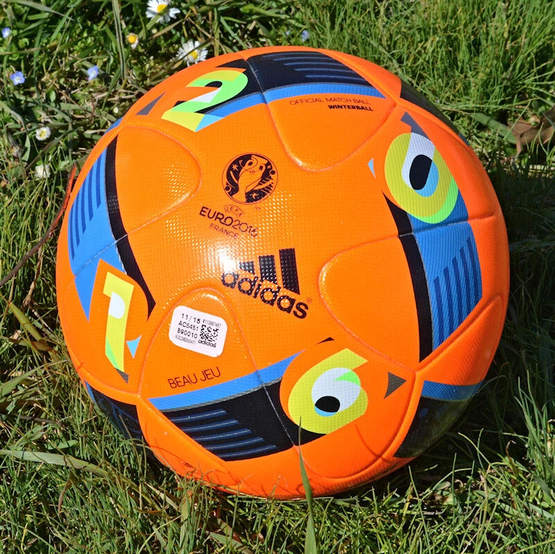 Pallone Adidas Beau Jeu Winter – vista completa su erba con grafica arancio fluo