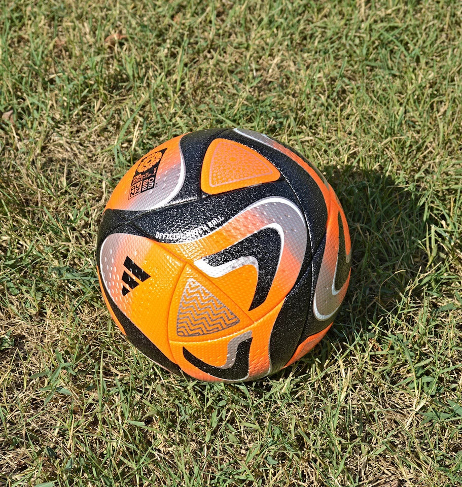 Pallone Adidas Oceaunz Pro Winter – vista completa su erba con grafica arancio fluo