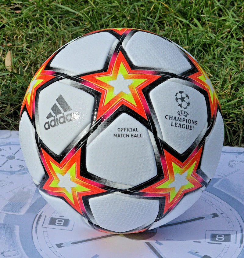 Pallone Adidas UCL 2021-2022 – vista completa su erba con grafica stella multicolore