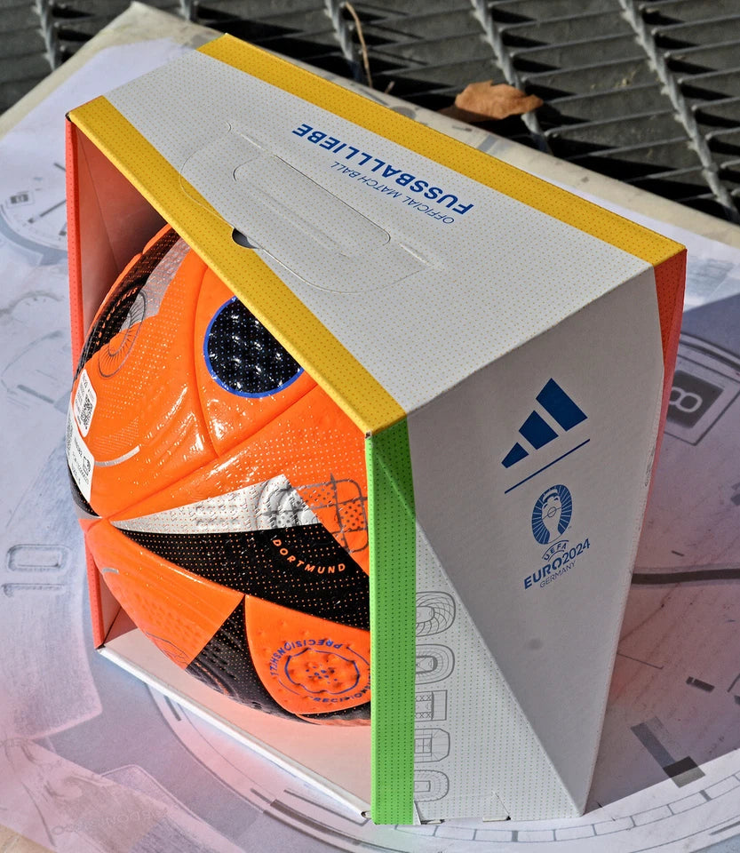 Pallone Adidas Fussballliebe Winter Pro – vista laterale con pannelli arancio e nero su erba